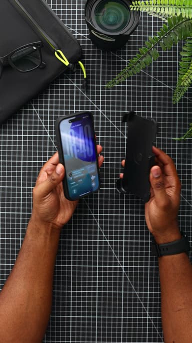 An iPhone 17 Pro in a black CLICK Latch Holster case held in one hand, and the empty belt-clip holster held clip-out in the other