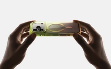 Two hands gently flexing a green-tinted CLICK Clear Ombre case, its translucency and MagSafe ring showing against a plain backdrop
